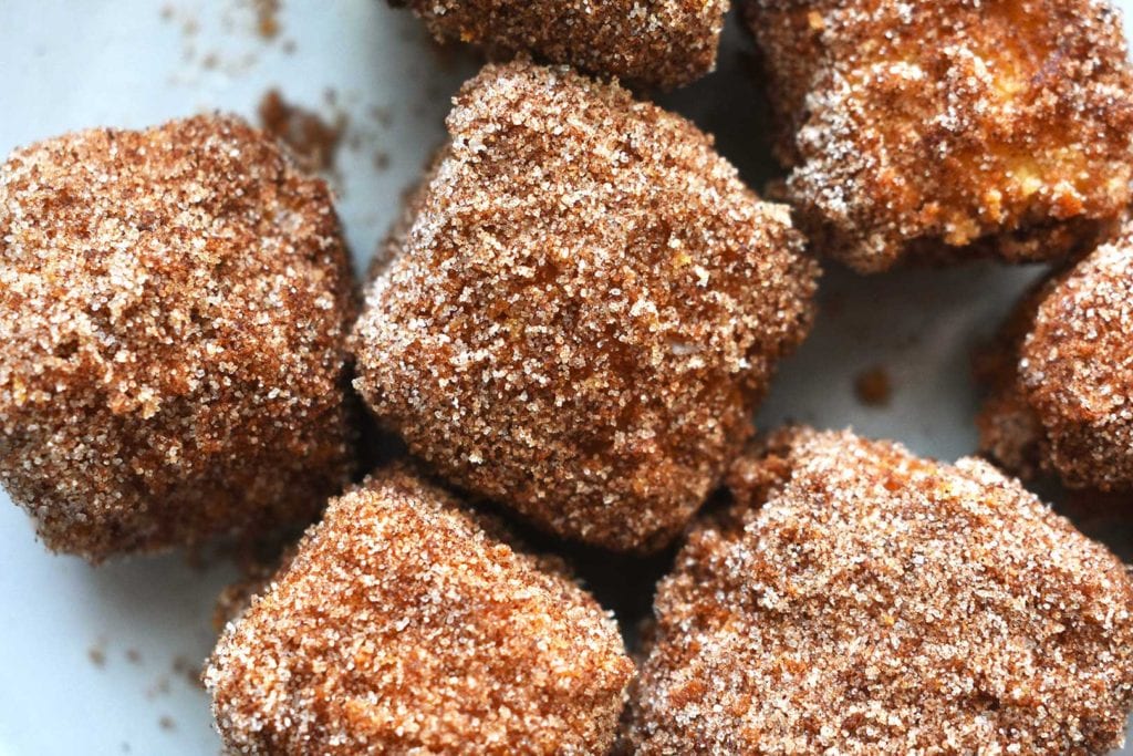 Close up photo of fried milk cubes dusted with cinnamon and sugar. 